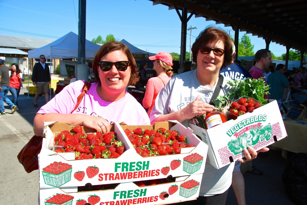 Two Mom's carry home flats of strawberries and a Delvin Farms CSA. 